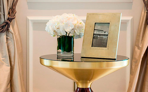 Nahaufnahme eines goldenen Beistelltisches dekoriert mit einem Bilderrahmen und einem weißen Blumenstrauß im Luxushotel in Hamburg